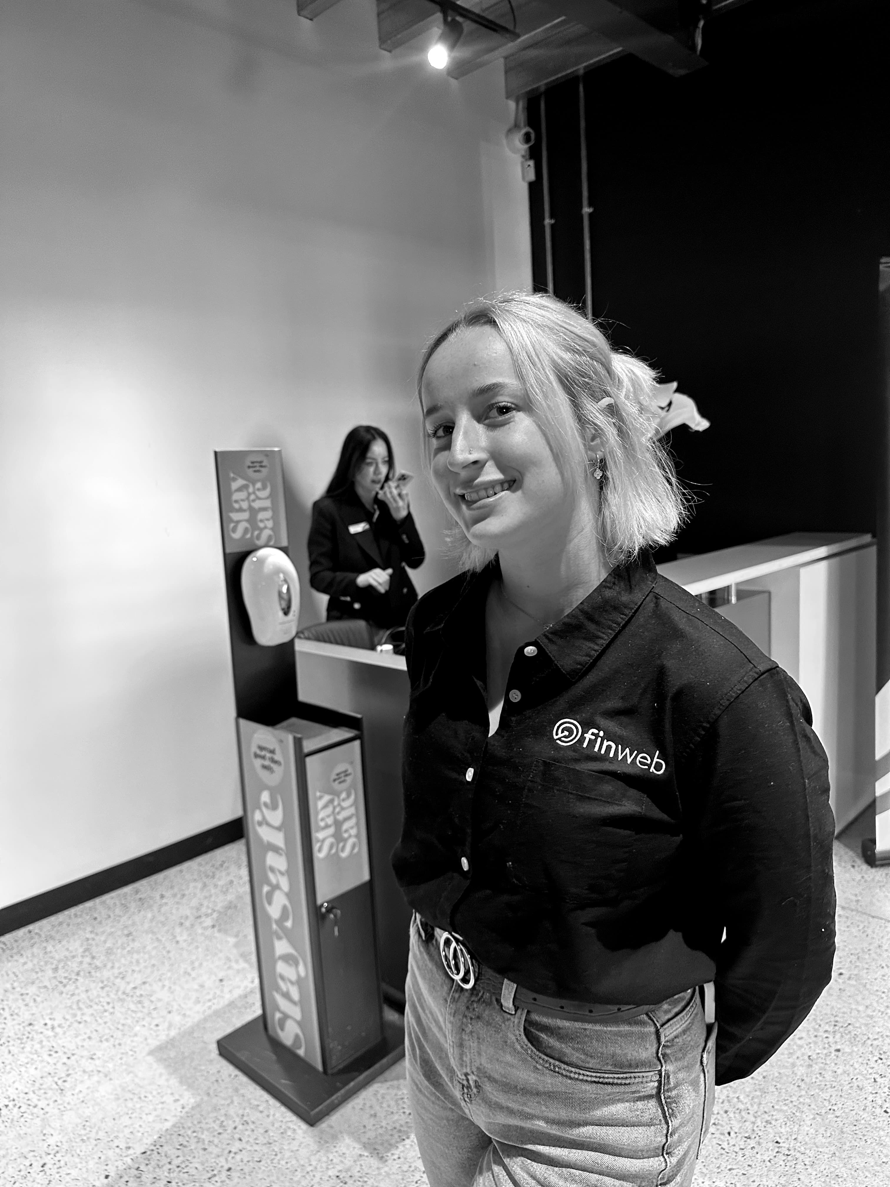 Smiling Finweb team member standing in a workplace reception area.